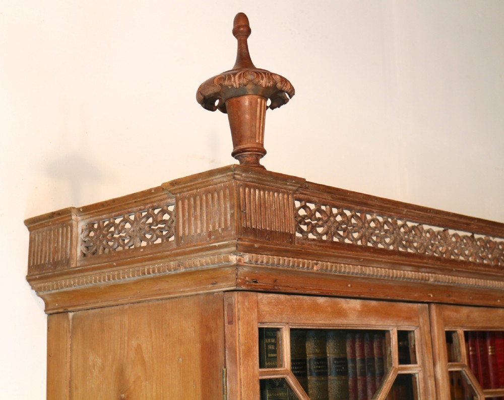 A large George III Chippendale period double bookcase crafted in natural pine, featuring astragal glazed upper doors topped with urn finials and lower panelled cupboards. View XXVIII