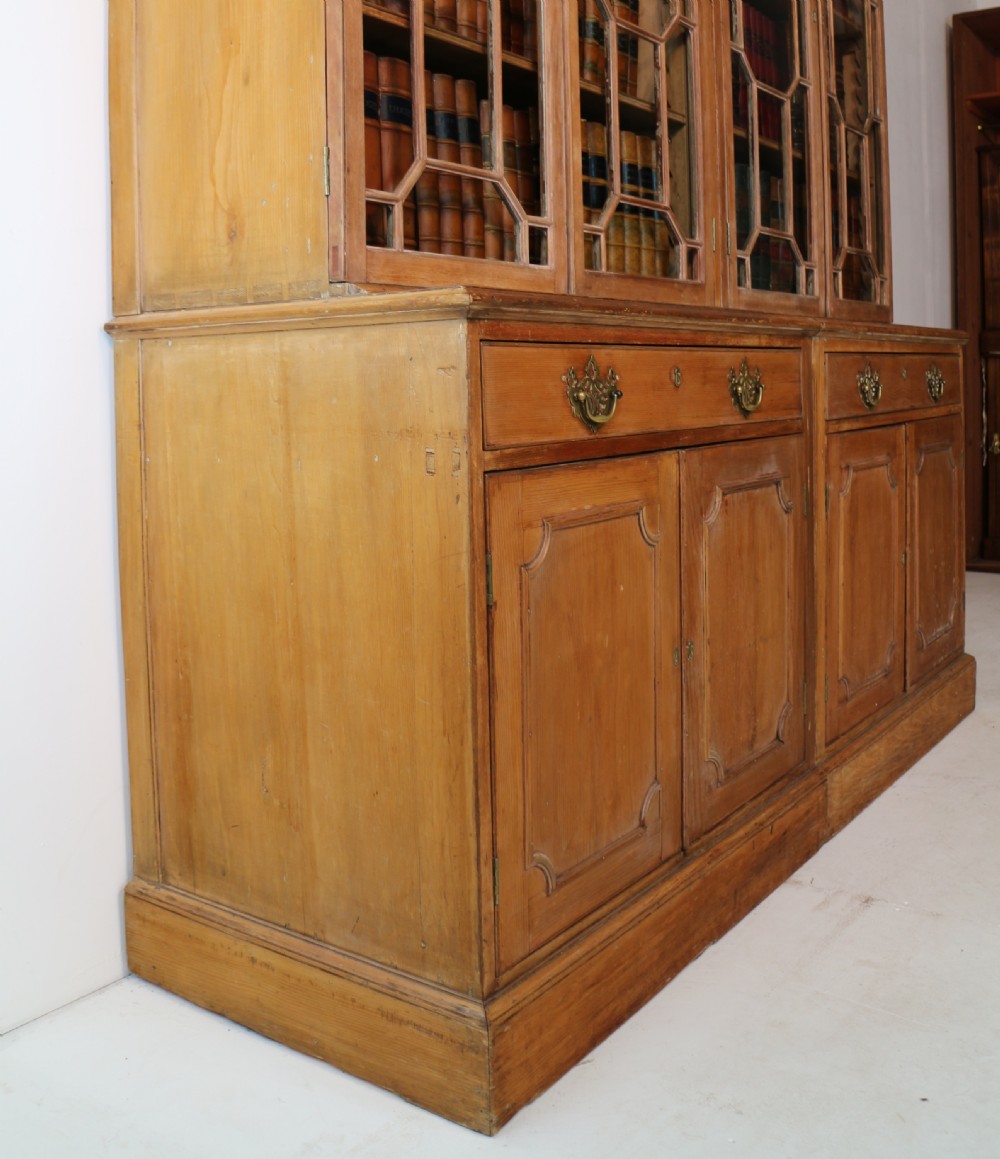 A large George III Chippendale period double bookcase crafted in natural pine, featuring astragal glazed upper doors topped with urn finials and lower panelled cupboards. View XXX