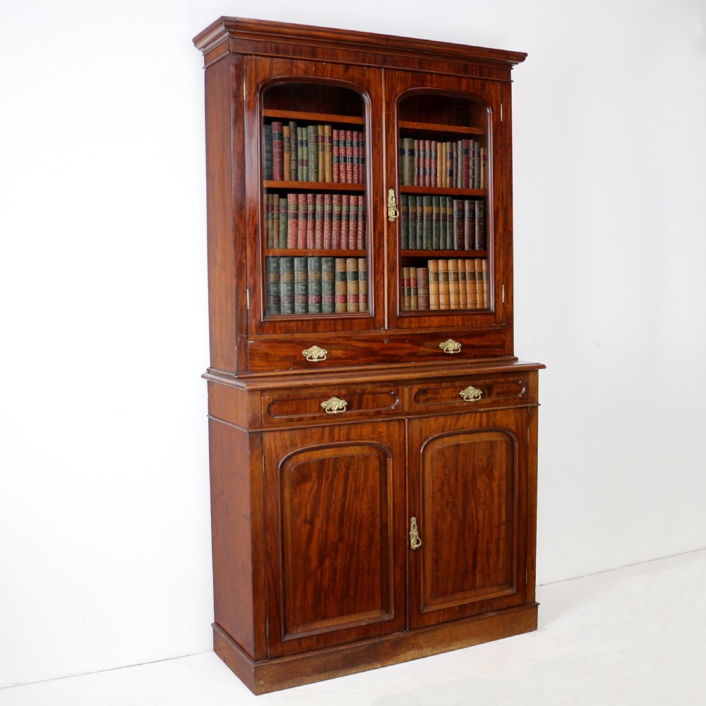 An early Victorian mahogany bookcase featuring an upper glazed section with two arched doors and a lower cupboard base with two drawers. View II