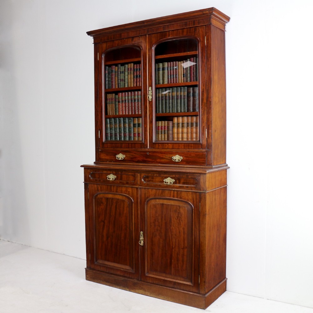 An early Victorian mahogany bookcase featuring an upper glazed section with two arched doors and a lower cupboard base with two drawers. View III