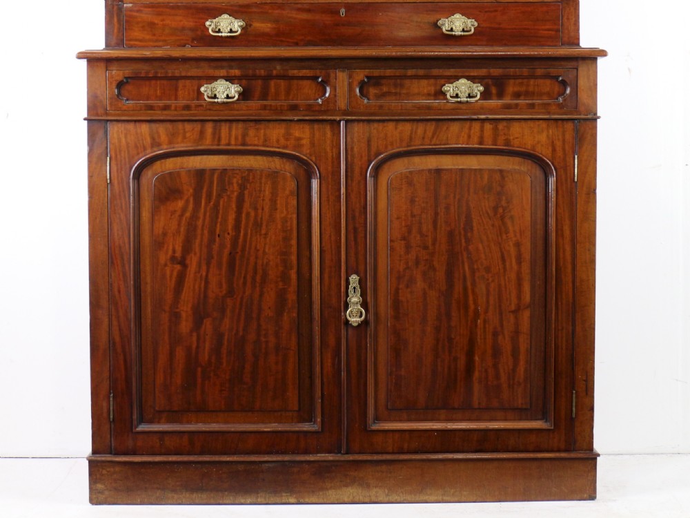 An early Victorian mahogany bookcase featuring an upper glazed section with two arched doors and a lower cupboard base with two drawers. View VIII