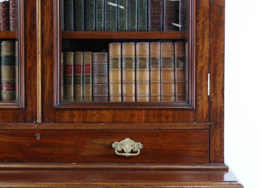 An early Victorian mahogany bookcase featuring an upper glazed section with two arched doors and a lower cupboard base with two drawers. View XII