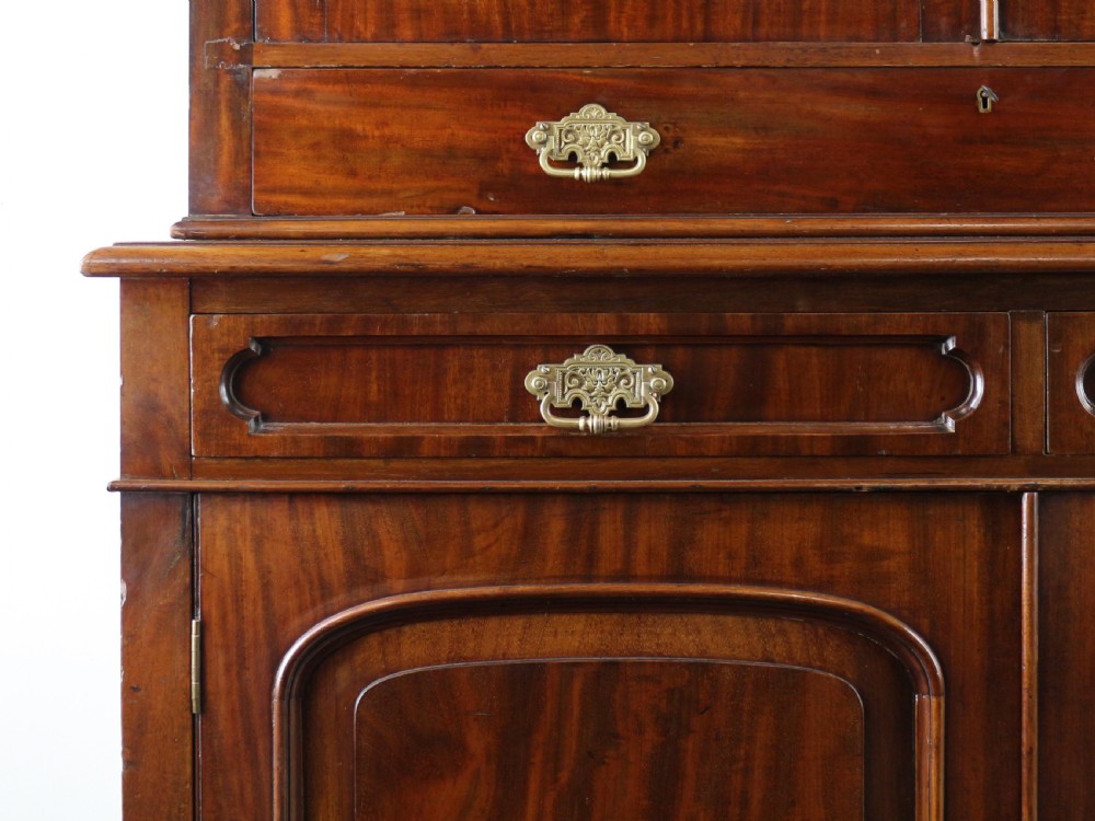 An early Victorian mahogany bookcase featuring an upper glazed section with two arched doors and a lower cupboard base with two drawers. View XIII