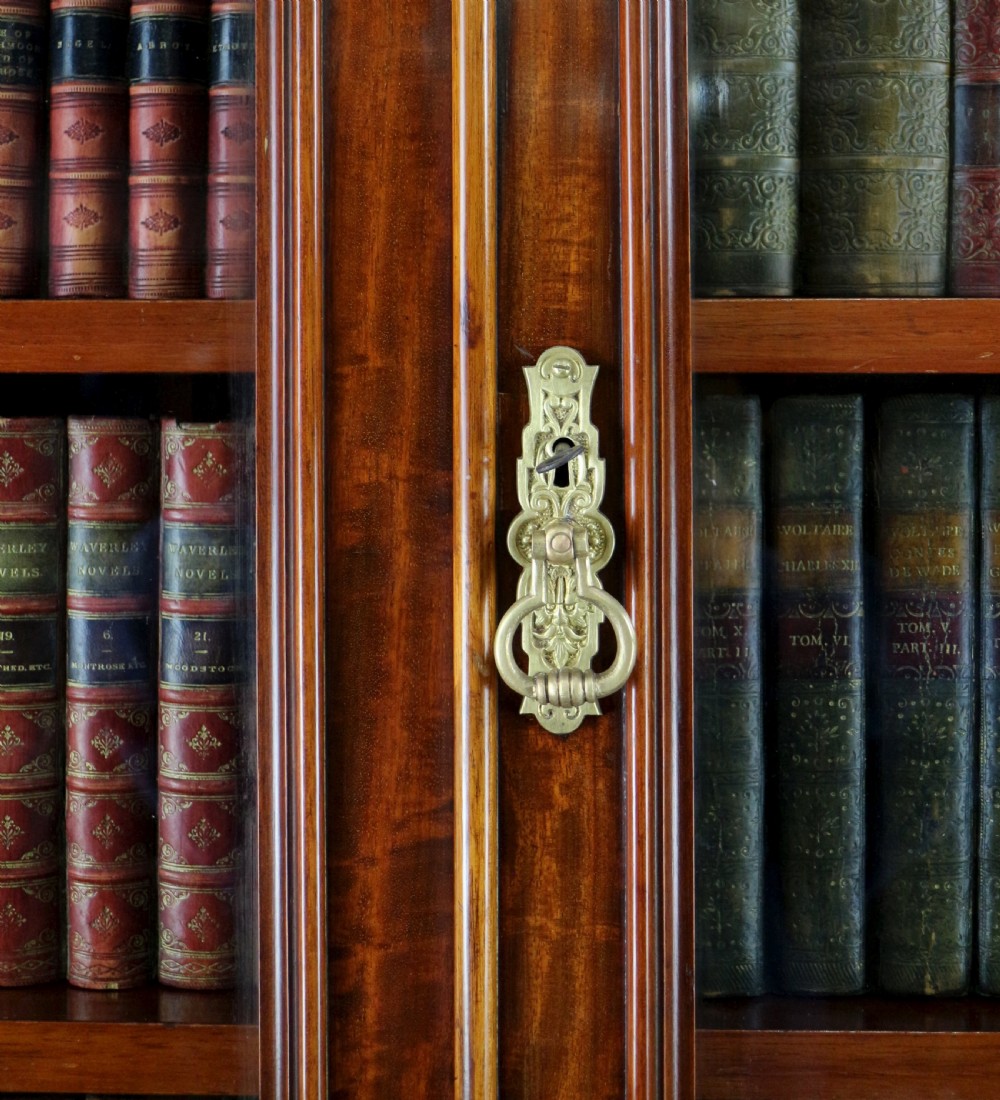 An early Victorian mahogany bookcase featuring an upper glazed section with two arched doors and a lower cupboard base with two drawers. View XIV
