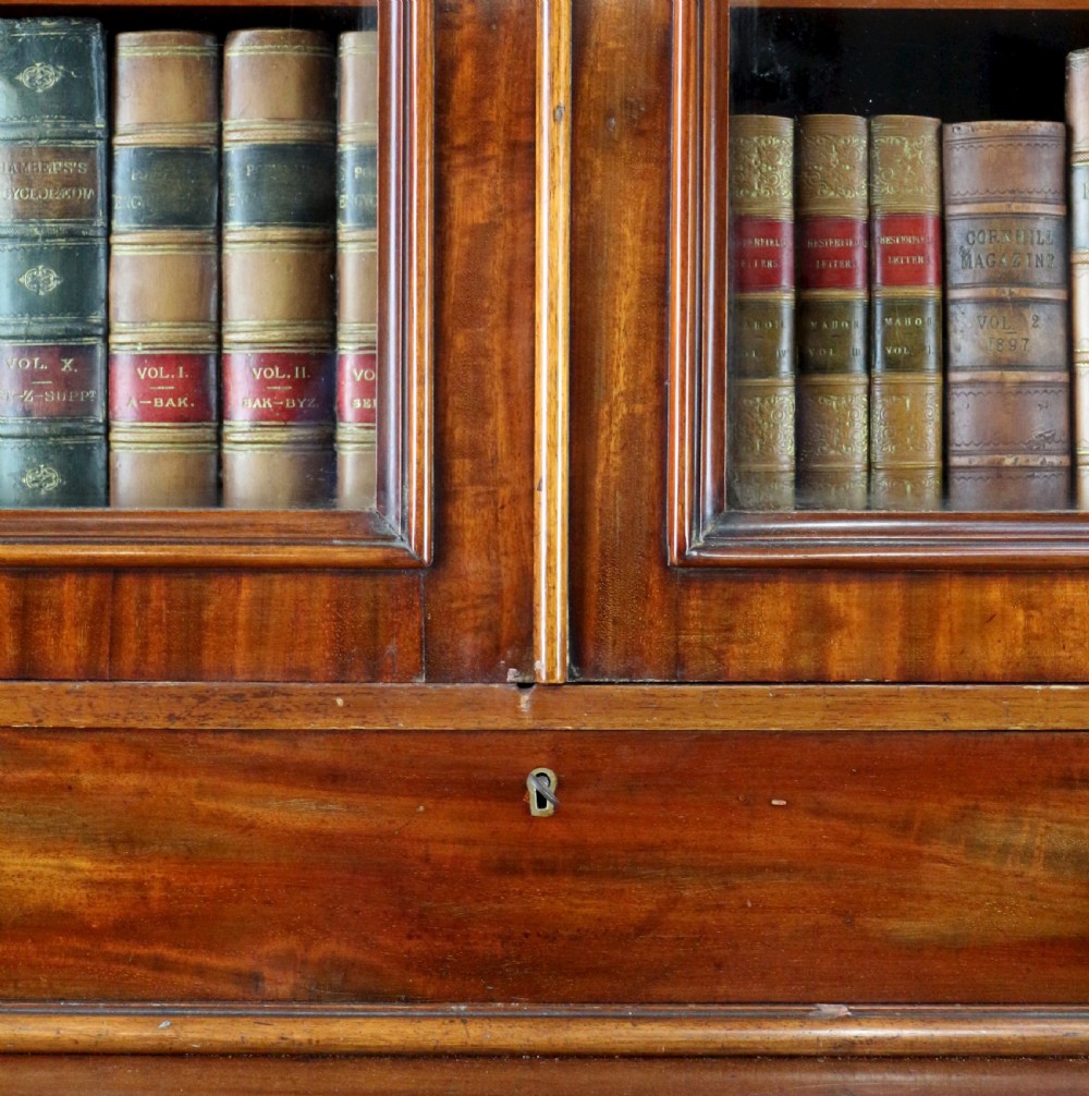 An early Victorian mahogany bookcase featuring an upper glazed section with two arched doors and a lower cupboard base with two drawers. View XVI
