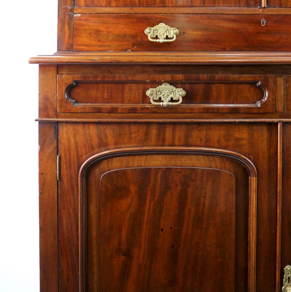 An early Victorian mahogany bookcase featuring an upper glazed section with two arched doors and a lower cupboard base with two drawers. View XVIII