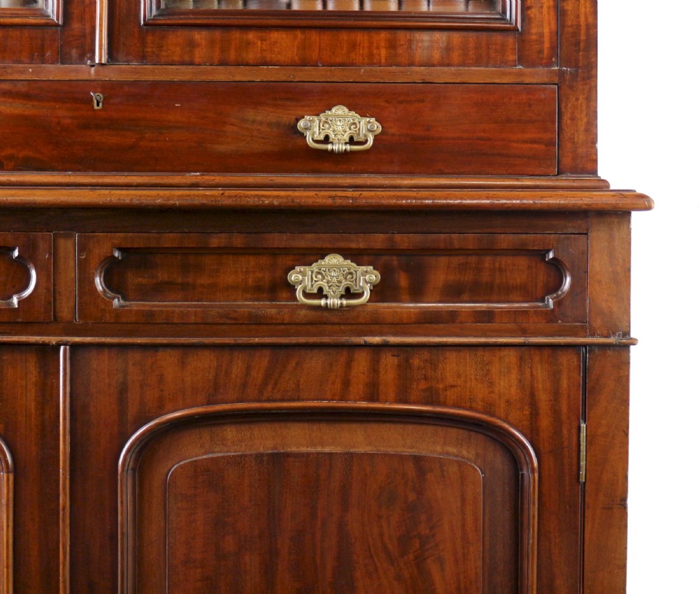 An early Victorian mahogany bookcase featuring an upper glazed section with two arched doors and a lower cupboard base with two drawers. View XIX