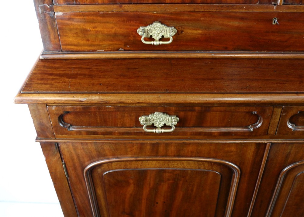 An early Victorian mahogany bookcase featuring an upper glazed section with two arched doors and a lower cupboard base with two drawers. View XXI