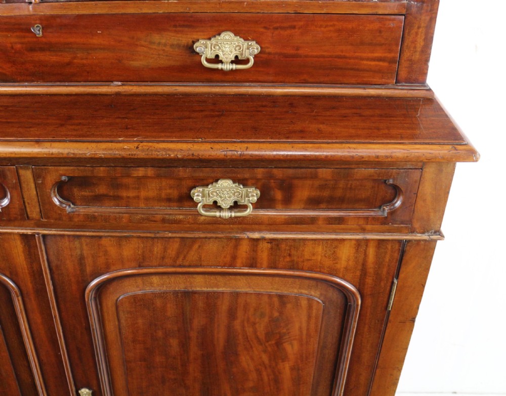 An early Victorian mahogany bookcase featuring an upper glazed section with two arched doors and a lower cupboard base with two drawers. View XXII