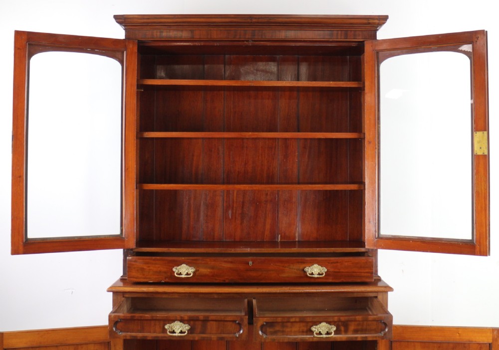 An early Victorian mahogany bookcase featuring an upper glazed section with two arched doors and a lower cupboard base with two drawers. View XXIV
