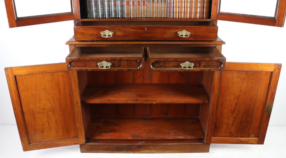 An early Victorian mahogany bookcase featuring an upper glazed section with two arched doors and a lower cupboard base with two drawers. View XXV