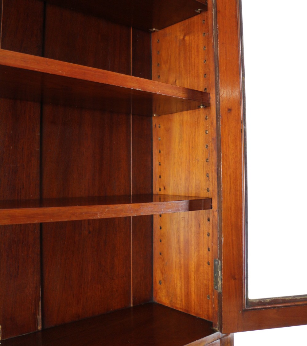 An early Victorian mahogany bookcase featuring an upper glazed section with two arched doors and a lower cupboard base with two drawers. View XXVI