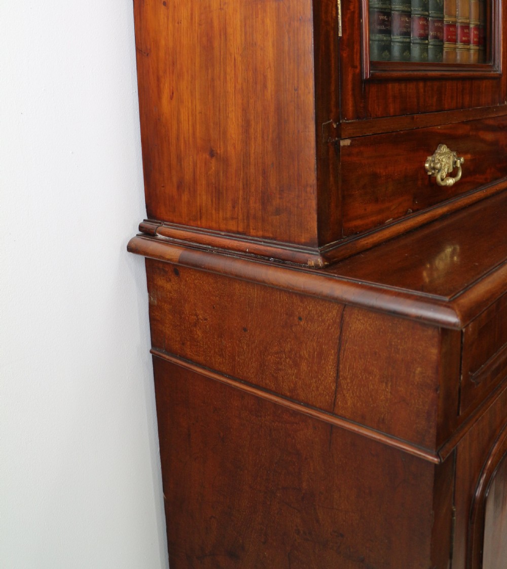 An early Victorian mahogany bookcase featuring an upper glazed section with two arched doors and a lower cupboard base with two drawers. View XXVIII