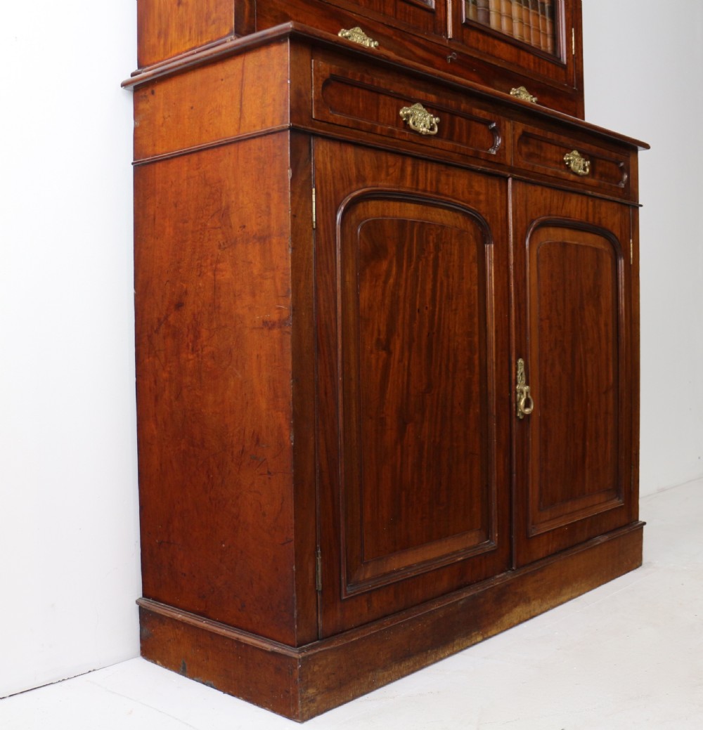 An early Victorian mahogany bookcase featuring an upper glazed section with two arched doors and a lower cupboard base with two drawers. View XXIX