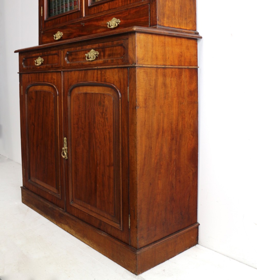An early Victorian mahogany bookcase featuring an upper glazed section with two arched doors and a lower cupboard base with two drawers. View XXXI