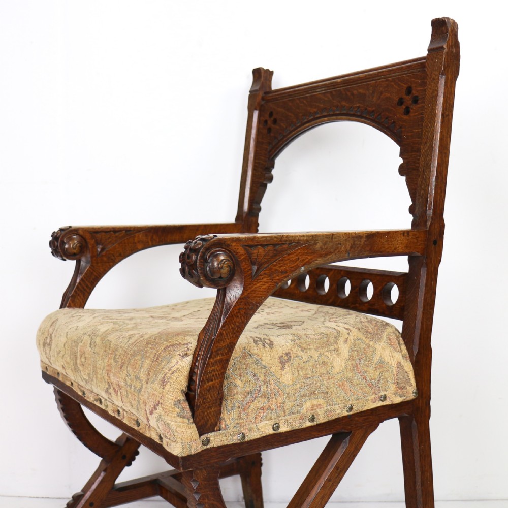 A Gothic Revival carved dark oak armchair featuring an arched backrest with quatrefoil cutouts, curved legs, and a patterned fabric seat. View V