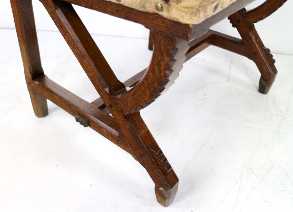 A Gothic Revival carved dark oak armchair featuring an arched backrest with quatrefoil cutouts, curved legs, and a patterned fabric seat. View VIII