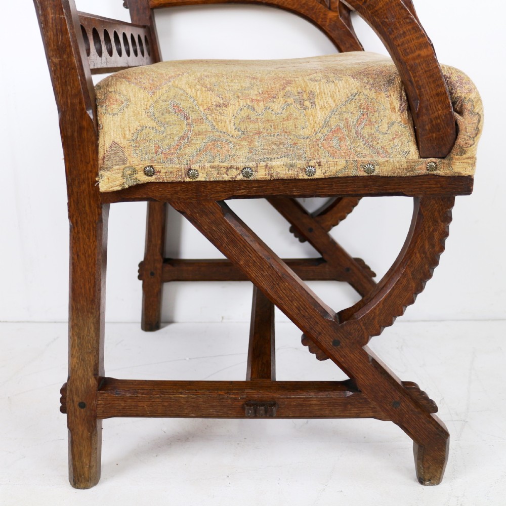 A Gothic Revival carved dark oak armchair featuring an arched backrest with quatrefoil cutouts, curved legs, and a patterned fabric seat. View XVII