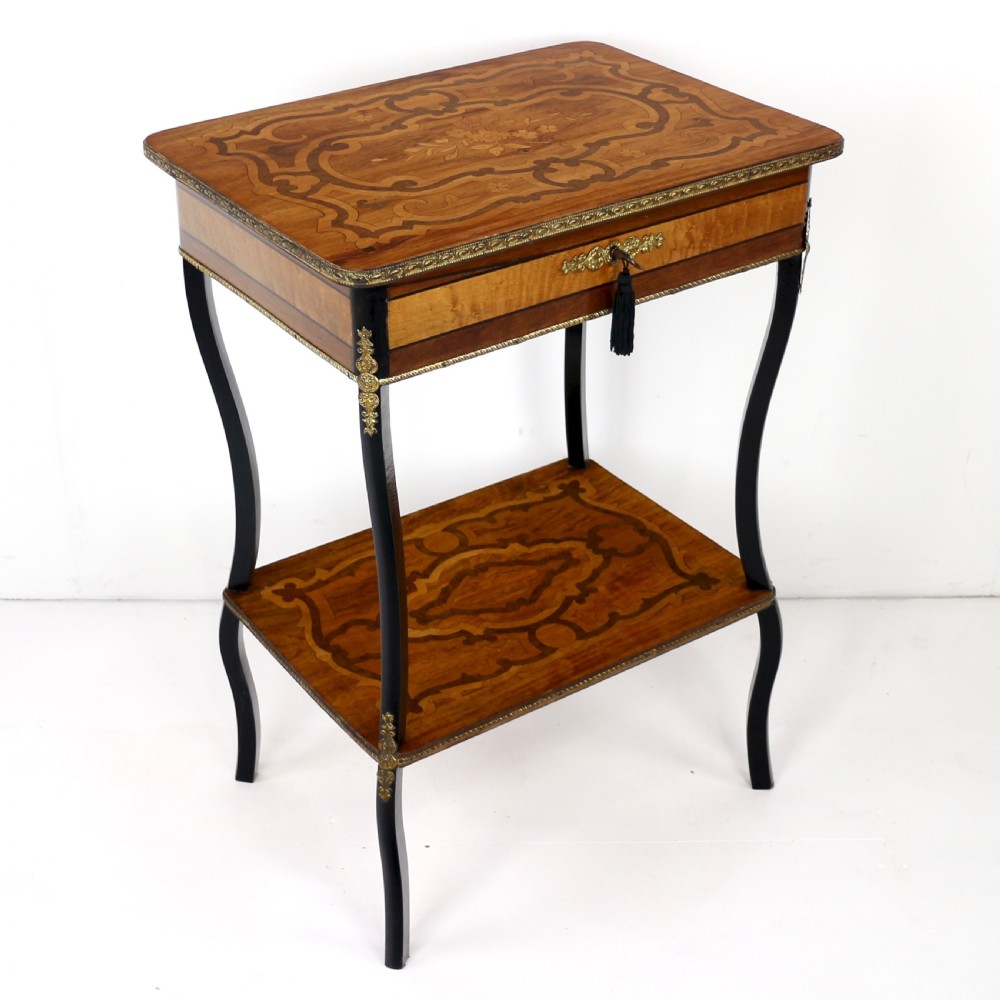 A late 19th-century French Napoleon III work table featuring floral marquetry inlays, ebonised legs, a single lockable drawer, and a lower shelf with brass mouldings.