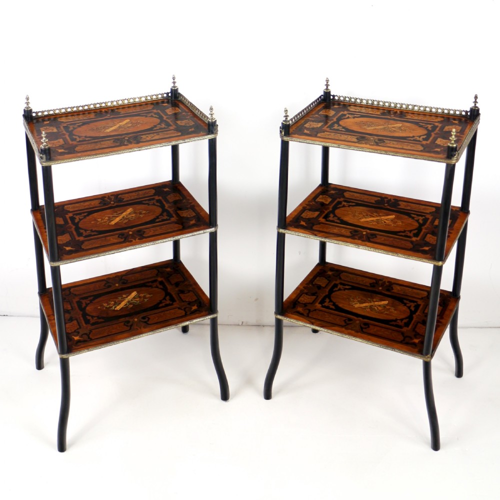 A pair of 19th-century French three-tier etageres featuring inlaid wood marquetry designs, ebonised legs, and pierced brass galleries on top.