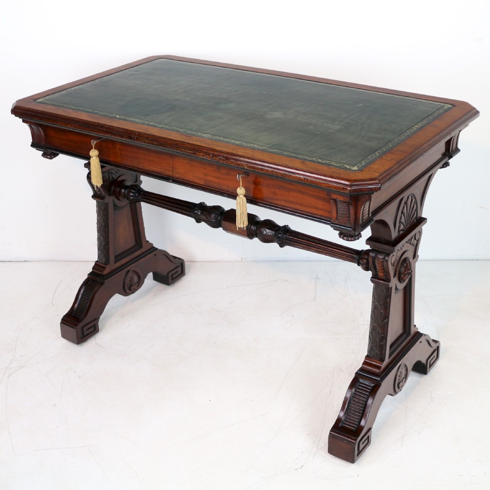 A Late Regency Neoclassical dark mahogany library table featuring a green leather inset writing surface, carved end supports with anthemion motifs, and frieze drawers with keys. View II