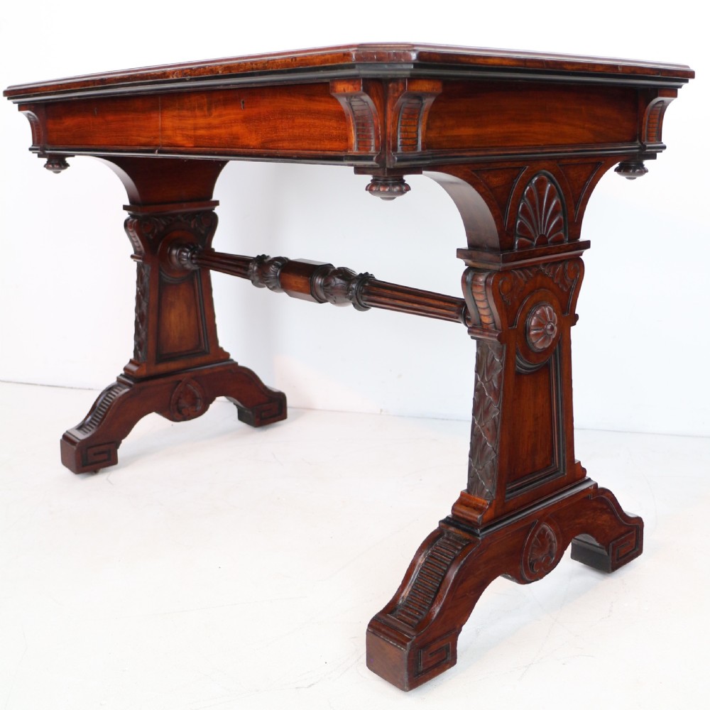 A Late Regency Neoclassical dark mahogany library table featuring a green leather inset writing surface, carved end supports with anthemion motifs, and frieze drawers with keys. View V