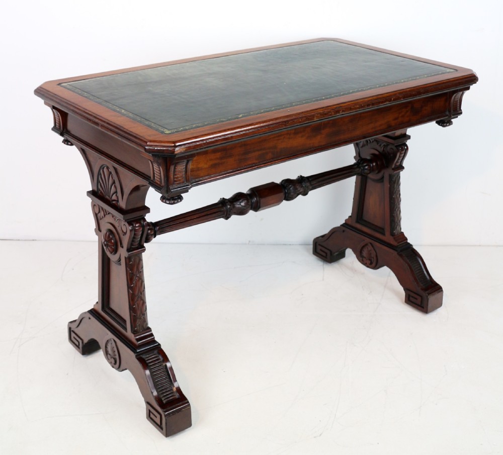 A Late Regency Neoclassical dark mahogany library table featuring a green leather inset writing surface, carved end supports with anthemion motifs, and frieze drawers with keys. View XII
