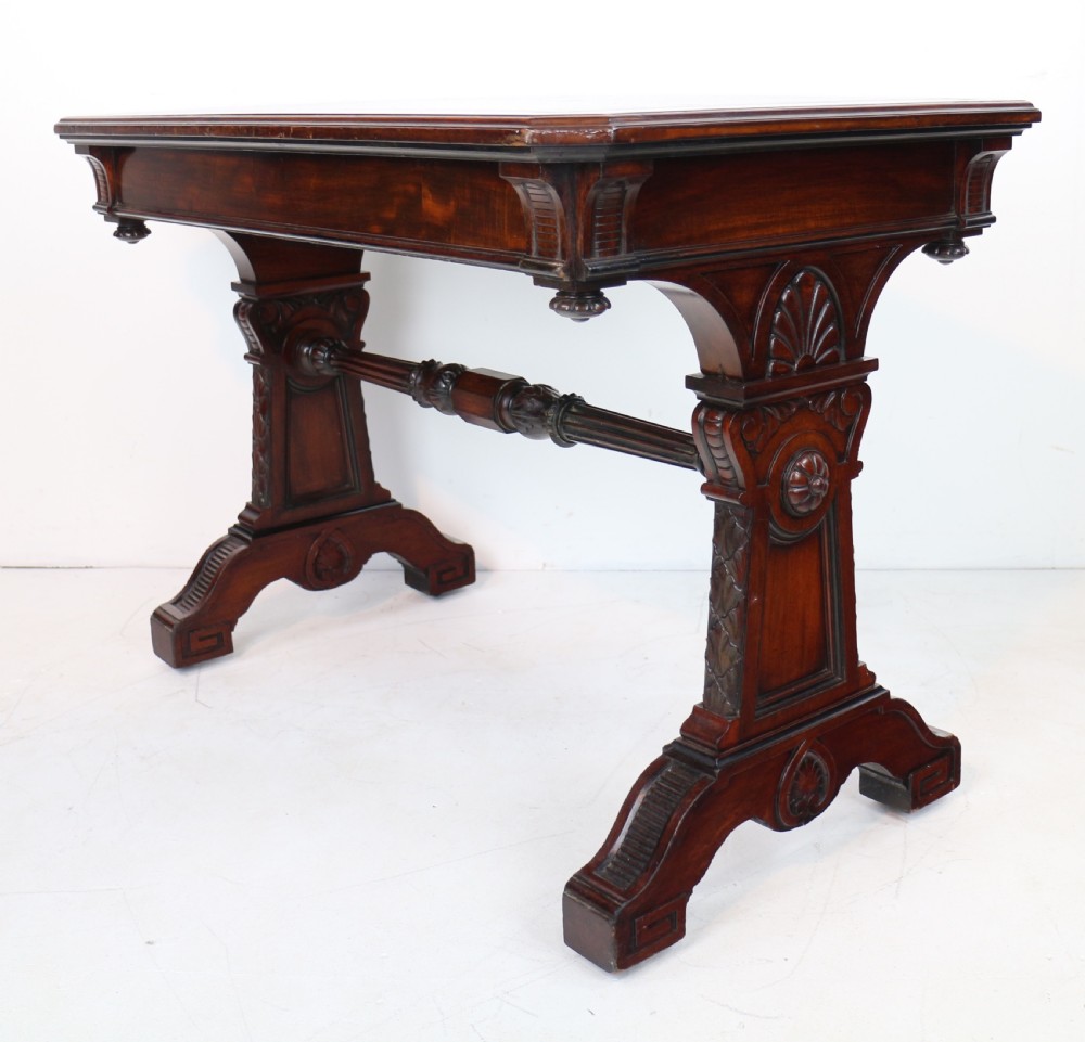 A Late Regency Neoclassical dark mahogany library table featuring a green leather inset writing surface, carved end supports with anthemion motifs, and frieze drawers with keys. View XIV