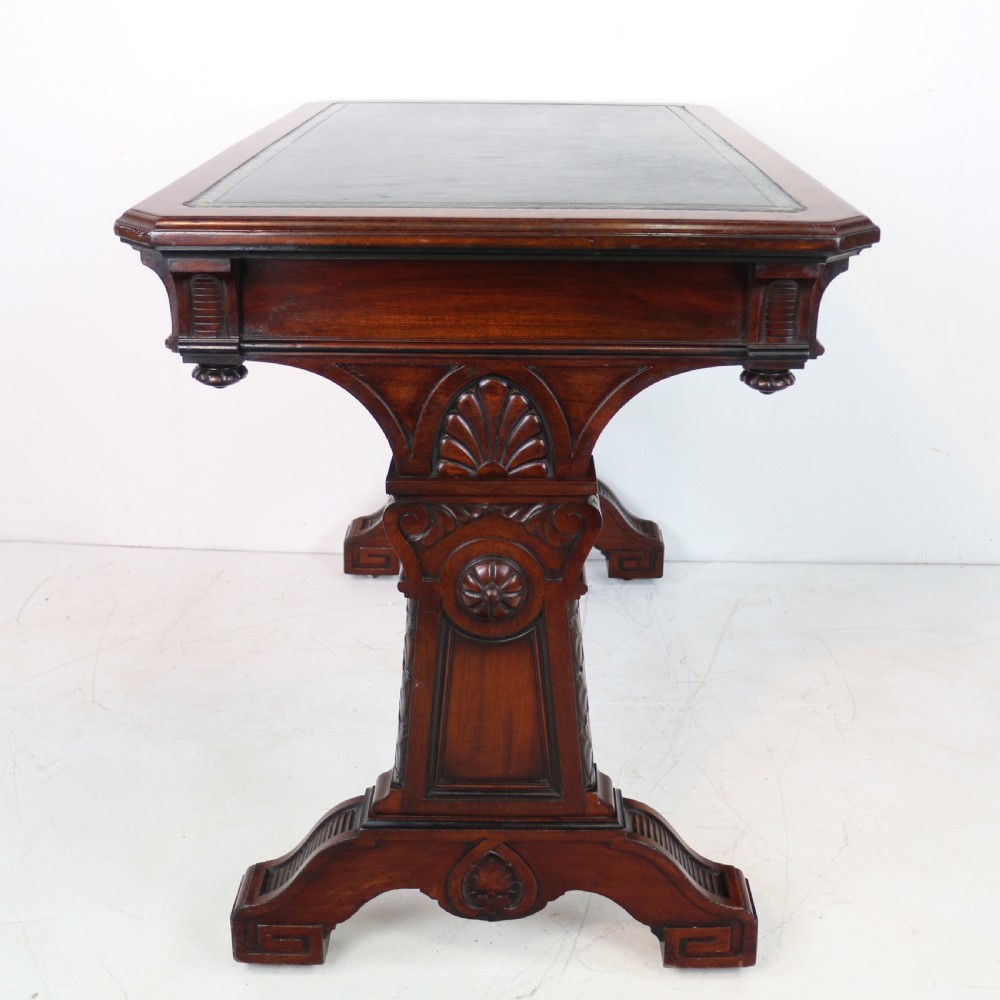 A Late Regency Neoclassical dark mahogany library table featuring a green leather inset writing surface, carved end supports with anthemion motifs, and frieze drawers with keys. View XV