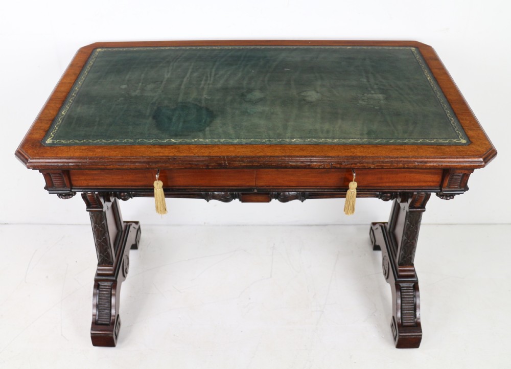 A Late Regency Neoclassical dark mahogany library table featuring a green leather inset writing surface, carved end supports with anthemion motifs, and frieze drawers with keys. View XVII