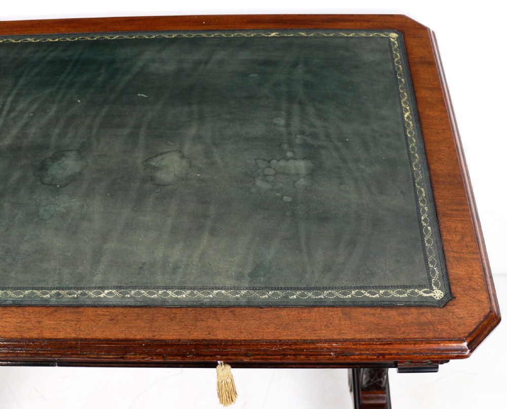 A Late Regency Neoclassical dark mahogany library table featuring a green leather inset writing surface, carved end supports with anthemion motifs, and frieze drawers with keys. View XIX