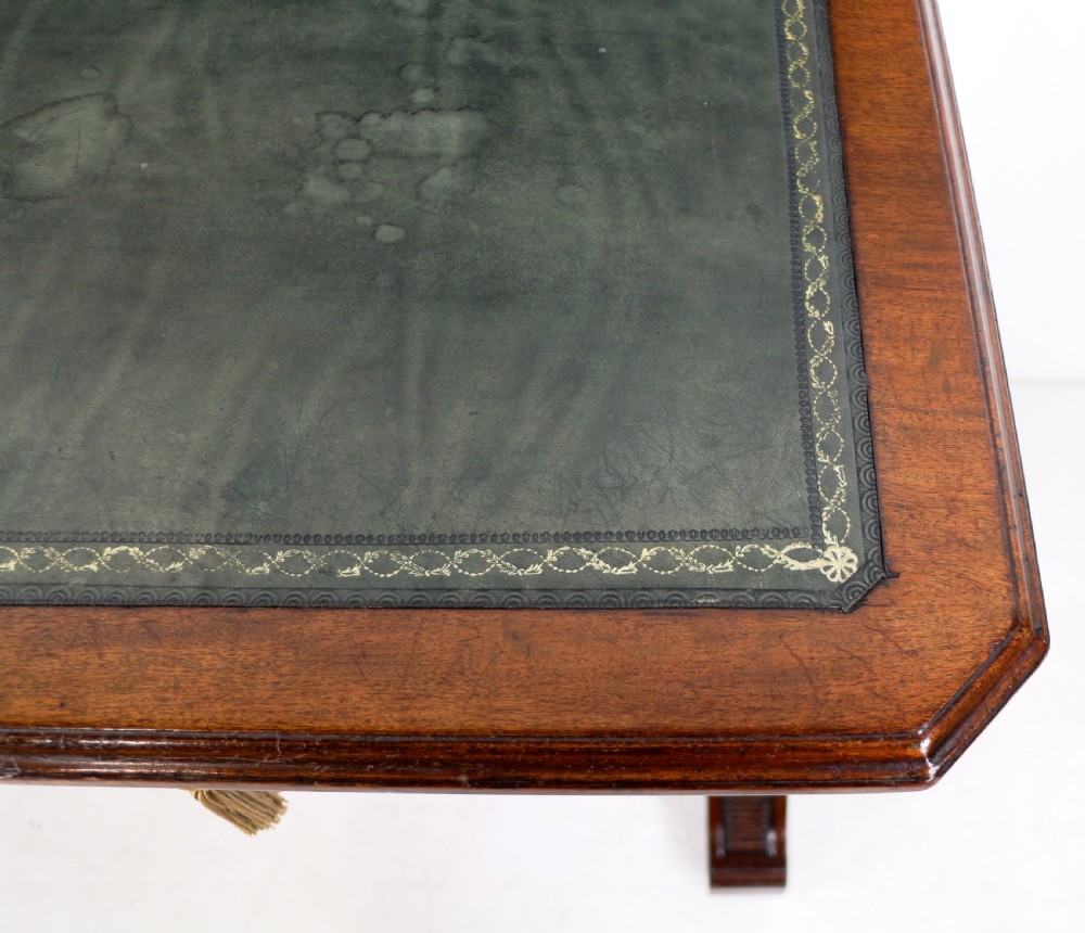 A Late Regency Neoclassical dark mahogany library table featuring a green leather inset writing surface, carved end supports with anthemion motifs, and frieze drawers with keys. View XX