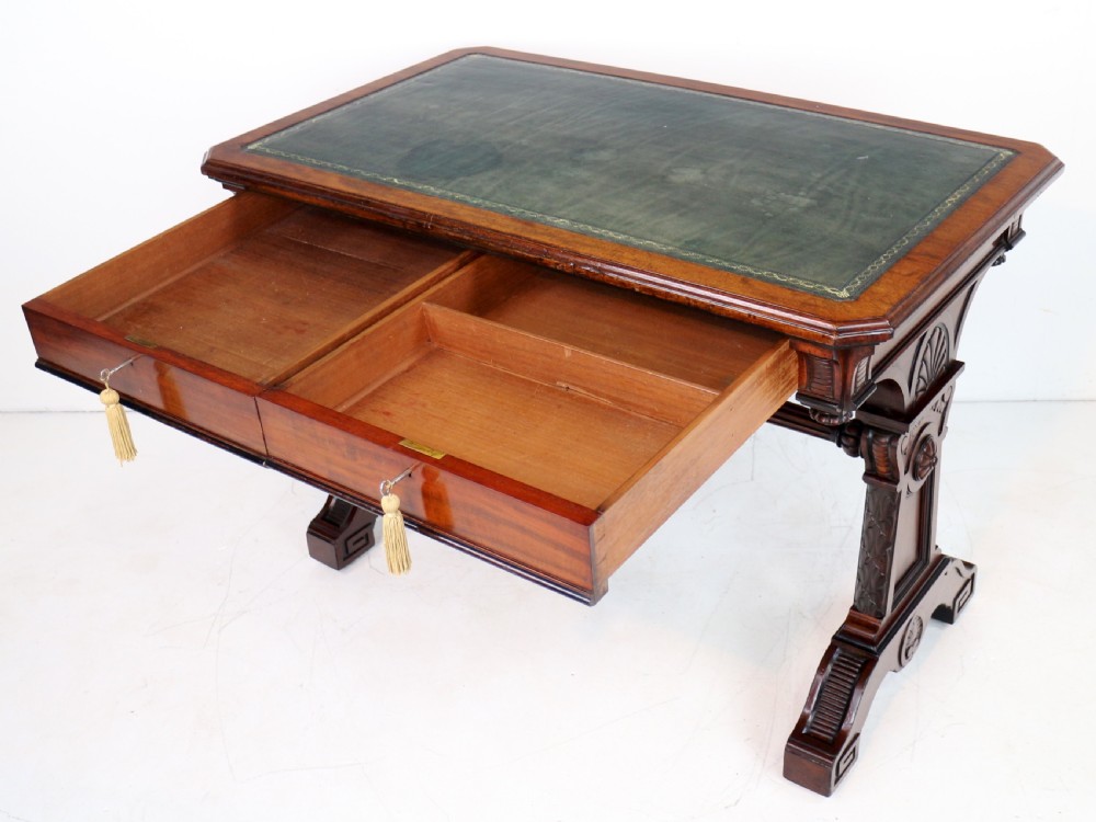 A Late Regency Neoclassical dark mahogany library table featuring a green leather inset writing surface, carved end supports with anthemion motifs, and frieze drawers with keys. View XXII