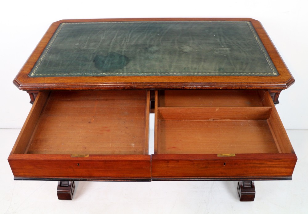 A Late Regency Neoclassical dark mahogany library table featuring a green leather inset writing surface, carved end supports with anthemion motifs, and frieze drawers with keys. View XXIII