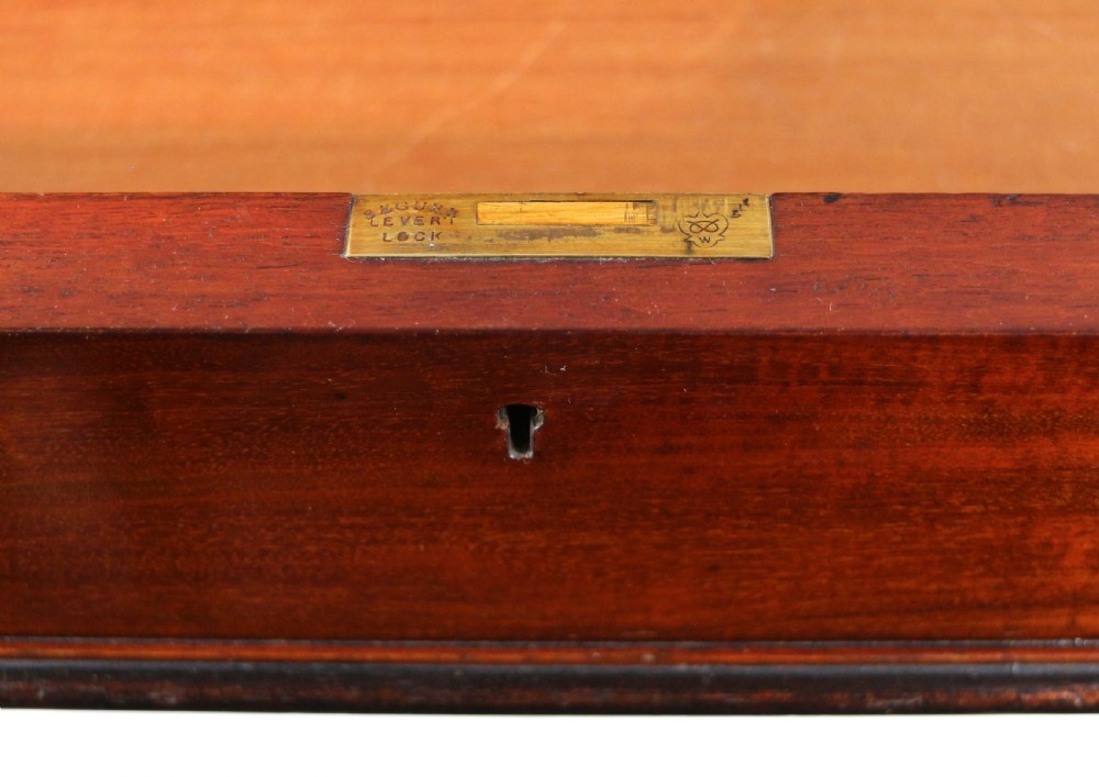 A Late Regency Neoclassical dark mahogany library table featuring a green leather inset writing surface, carved end supports with anthemion motifs, and frieze drawers with keys. View XXV