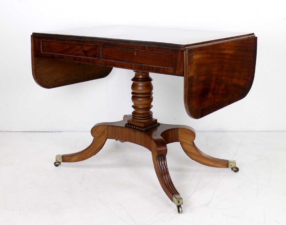 A Regency mahogany drop-leaf sofa table with frieze drawers, turned pedestal, reeded quadrupod legs, and brass castors. View III