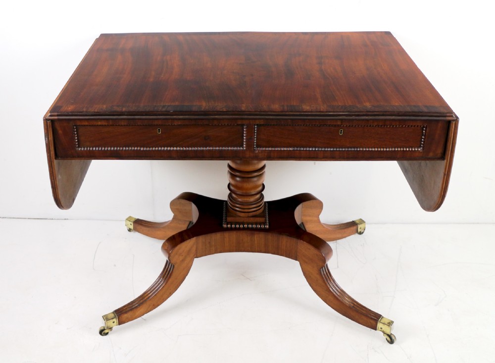 A Regency mahogany drop-leaf sofa table with frieze drawers, turned pedestal, reeded quadrupod legs, and brass castors. View VI