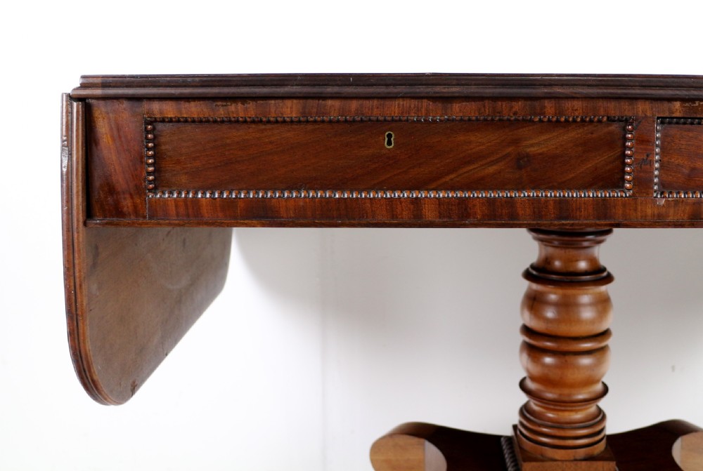 A Regency mahogany drop-leaf sofa table with frieze drawers, turned pedestal, reeded quadrupod legs, and brass castors. View VII