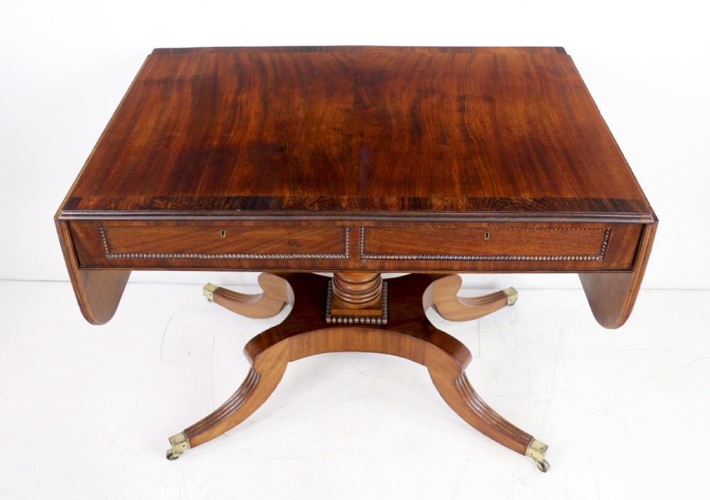 A Regency mahogany drop-leaf sofa table with frieze drawers, turned pedestal, reeded quadrupod legs, and brass castors. View VIII