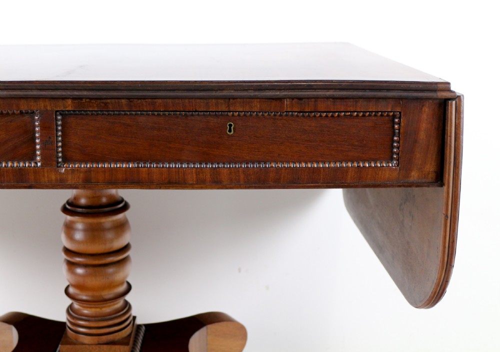 A Regency mahogany drop-leaf sofa table with frieze drawers, turned pedestal, reeded quadrupod legs, and brass castors. View X