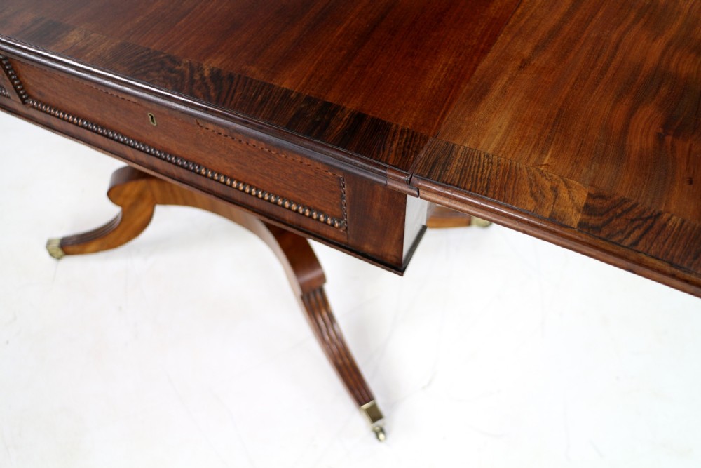 A Regency mahogany drop-leaf sofa table with frieze drawers, turned pedestal, reeded quadrupod legs, and brass castors. View XIII