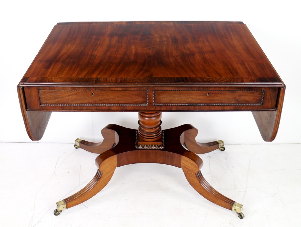 A Regency mahogany drop-leaf sofa table with frieze drawers, turned pedestal, reeded quadrupod legs, and brass castors. View XIV