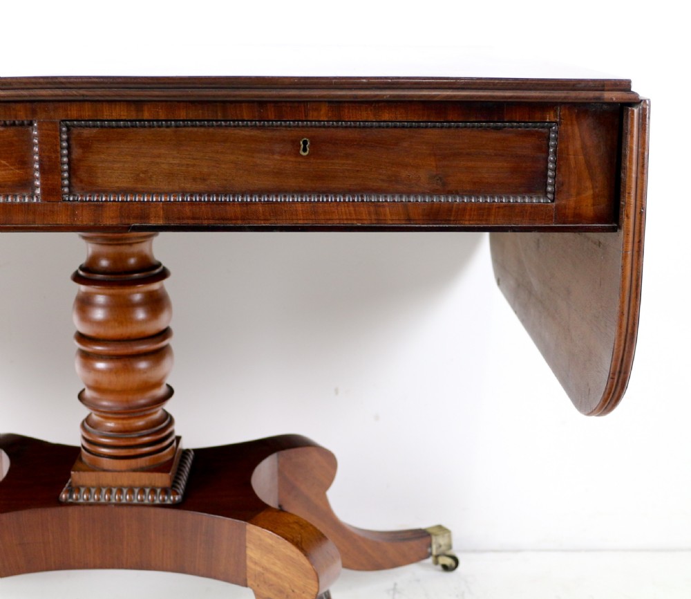A Regency mahogany drop-leaf sofa table with frieze drawers, turned pedestal, reeded quadrupod legs, and brass castors. View XIX