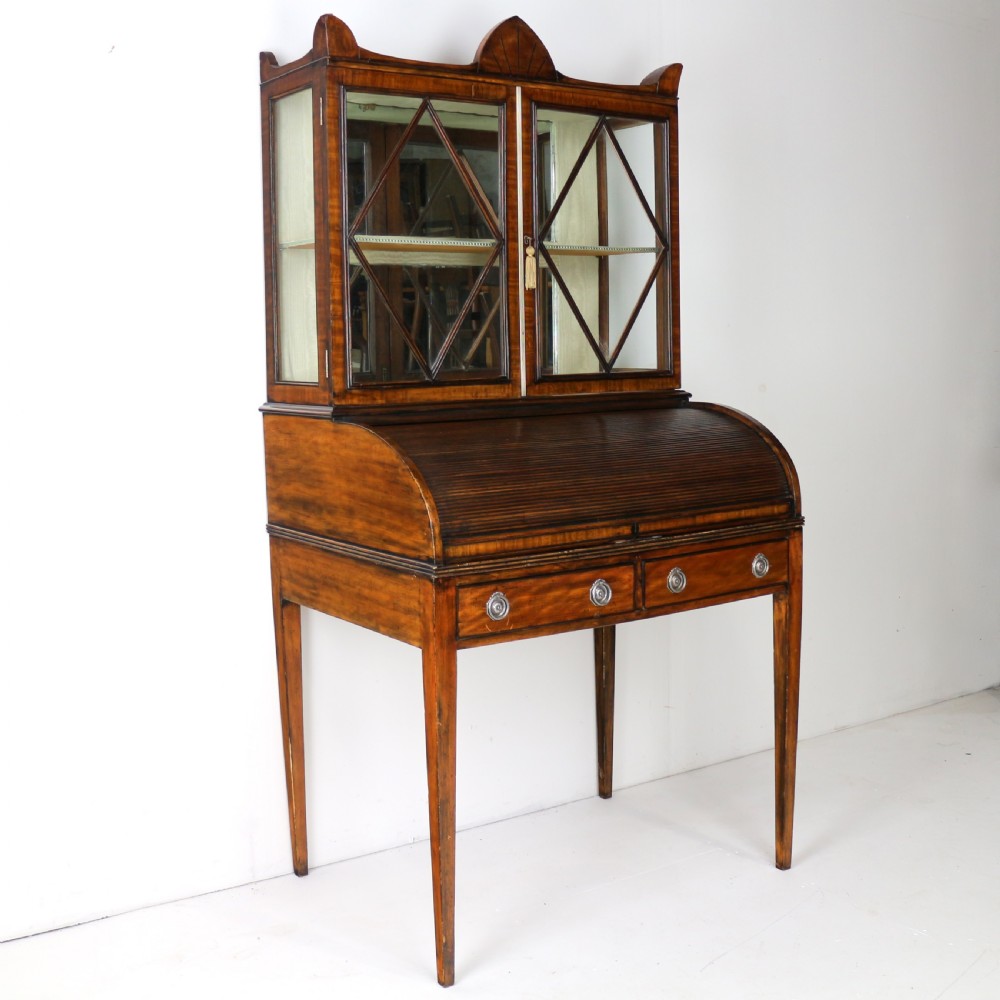An antique mahogany writing desk cabinet featuring an upper glass cabinet with diamond glazing bars, a curved slatted tambour shutter section, and two drawers on square tapered legs. View II