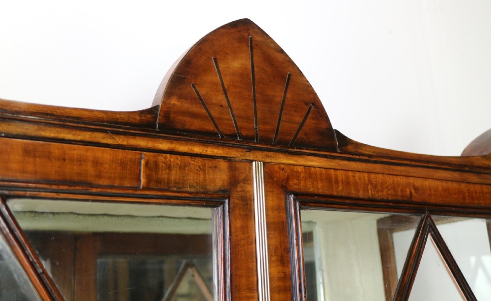 An antique mahogany writing desk cabinet featuring an upper glass cabinet with diamond glazing bars, a curved slatted tambour shutter section, and two drawers on square tapered legs. View XII