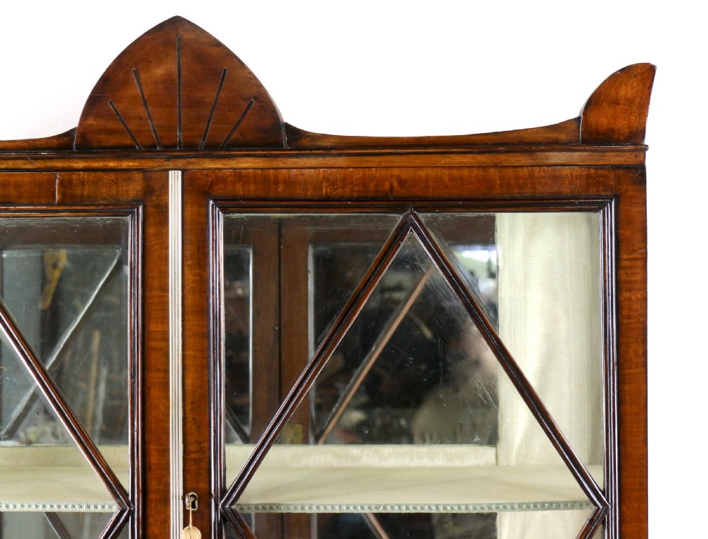 An antique mahogany writing desk cabinet featuring an upper glass cabinet with diamond glazing bars, a curved slatted tambour shutter section, and two drawers on square tapered legs. View XIII