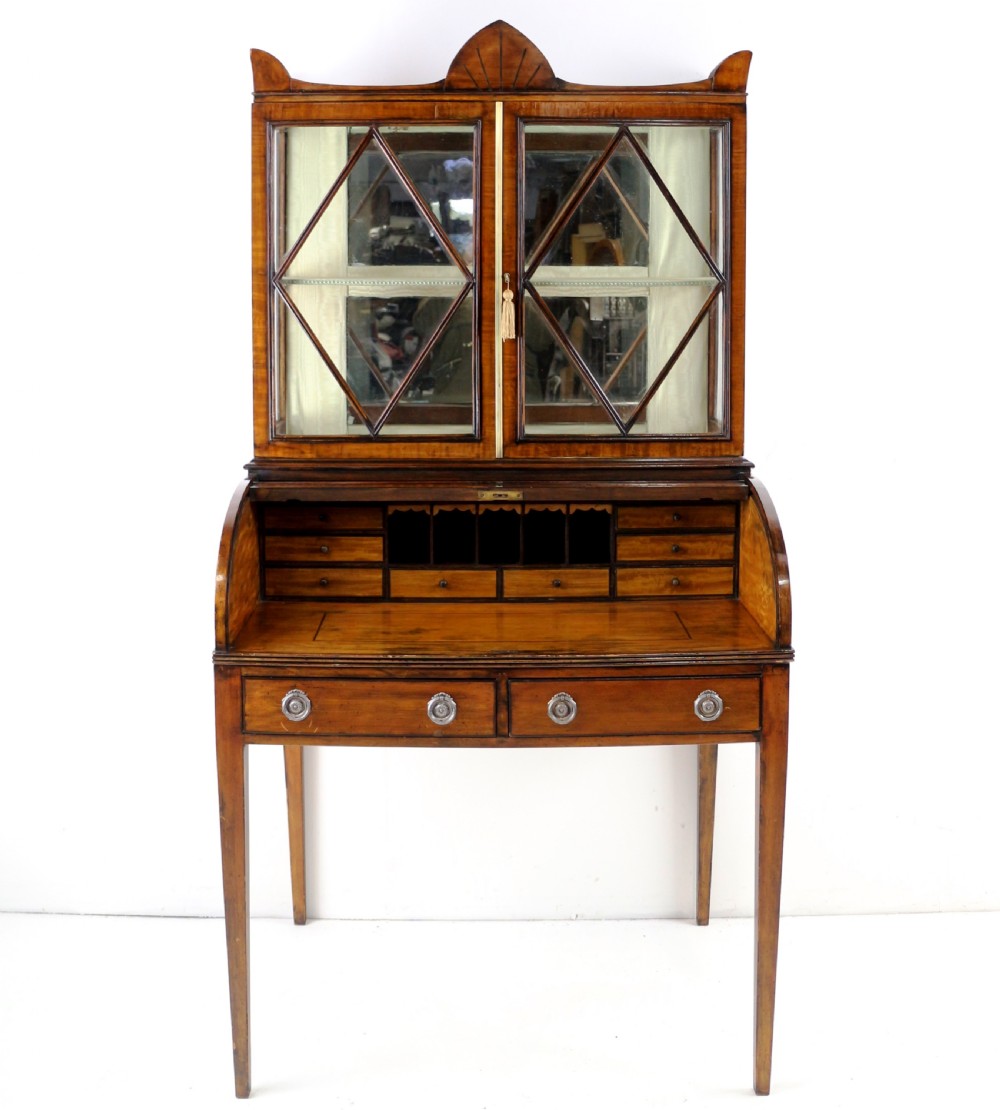 An antique mahogany writing desk cabinet featuring an upper glass cabinet with diamond glazing bars, a curved slatted tambour shutter section, and two drawers on square tapered legs. View XVIII