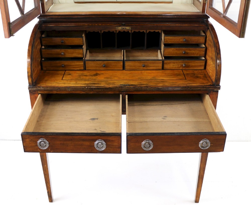 An antique mahogany writing desk cabinet featuring an upper glass cabinet with diamond glazing bars, a curved slatted tambour shutter section, and two drawers on square tapered legs. View XXIII