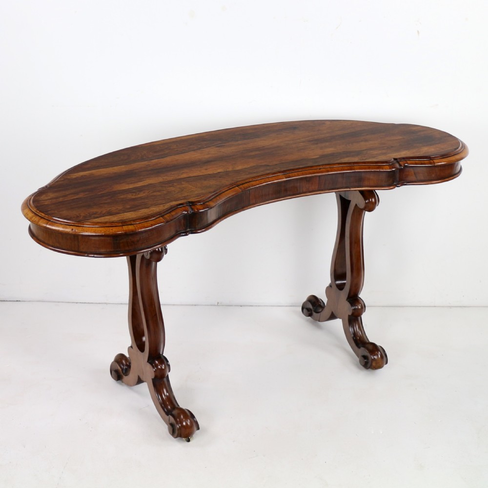 A Victorian rosewood kidney-shaped writing table with a figured timber top supported by carved lyre legs ending in scroll feet. View II