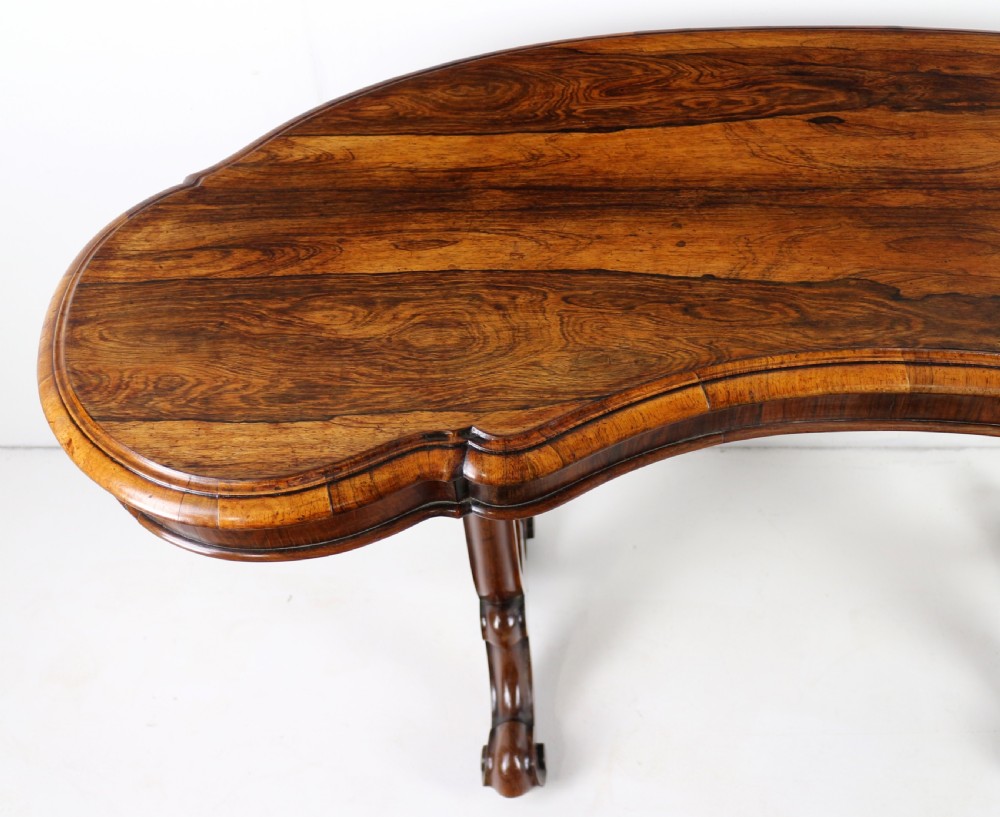 A Victorian rosewood kidney-shaped writing table with a figured timber top supported by carved lyre legs ending in scroll feet. View XI